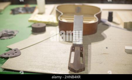 Riparazione della chitarra. Laboratorio di chitarra in legno. Incollaggio degli attrezzi. Dettagli di fabbricazione del caso. Foto Stock