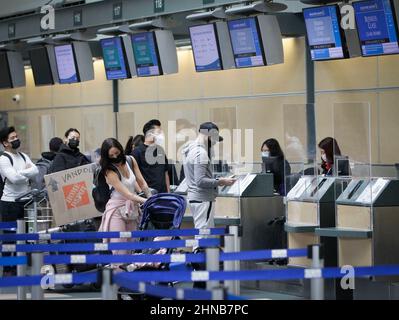 Richmond, Canada. 15th Feb 2022. I viaggiatori che indossano maschere facciali si allineano di fronte ai banchi delle compagnie aeree dell'aeroporto internazionale di Vancouver a Richmond, British Columbia, Canada, il 15 febbraio 2022. Il Canada sta allentando i requisiti dei test all'arrivo per i viaggiatori completamente vaccinati a partire dal 28 febbraio, poiché l'ultima ondata di COVID-19 guidata dalla variante Omicron ha superato il suo picco, l'Agenzia per la Sanità pubblica del Canada ha annunciato Martedì. Credit: Liang Sen/Xinhua/Alamy Live News Foto Stock