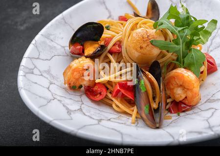 Spaghetti con frutti di mare, capesante, gamberi, cozze su sfondo scuro con spazio per il testo Foto Stock