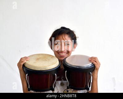 Allegro giovane e carino giocatore di bongo messicano (percussionista) sorride con la sua coppia di bongos (batteria bongo) e guarda lo spettatore. Foto Stock