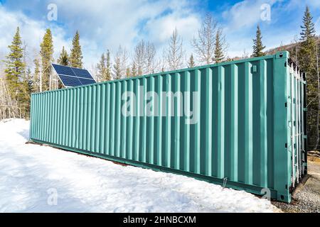 Pannelli solari montati all'esterno di un contenitore di spedizione ridestinato per la generazione di energia remota. Foto Stock