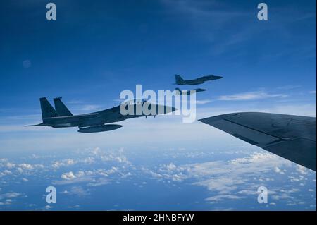 Tre aquile dell'aeronautica degli Stati Uniti F-15C assegnate al 67th Fighter Squadron, Kadena Air base, Giappone, volano accanto ad un US Air Force KC-135 Stratotanker assegnato al 909th Air Refeling Squadron, Kadena Air base, Giappone, sopra l'Oceano Pacifico, durante l'esercizio Cope North 22, 10 febbraio 2022. La F-15 è un combattente tattico per tutte le stagioni, estremamente manovrabile, progettato per consentire all'Air Force di conquistare e mantenere la supremazia aerea sul campo di battaglia. (STATI UNITI Air Force foto di Tech. SGT. Matthew Lotz) Foto Stock