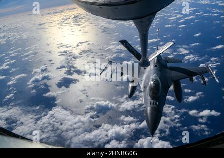 US Air Force KC-135 Stratotanker assegnato al 909th Air Refeling Squadron, Kadena Air base, Giappone, si prepara a rifornire un US Air Force F-16 Fighting Falcons assegnato al 14th Fighter Squadron, Misawa Air base, Giappone, sopra l'Oceano Pacifico, durante l'esercizio Cope North 2022, 10 febbraio 2022. Il F-16 è un aereo da combattimento compatto e multirole altamente manovrabile e collaudato nei combattimenti aria-aria e negli attacchi aria-superficie. (STATI UNITI Air Force foto di Tech. SGT. Matthew Lotz) Foto Stock