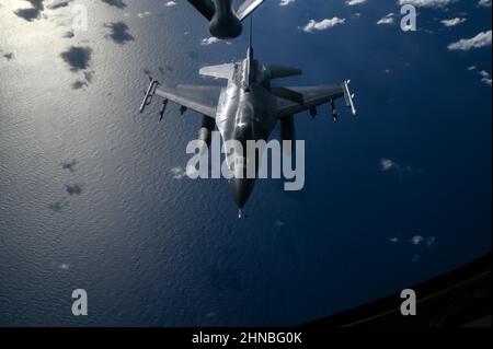 Un US Air Force KC-135 Stratotanker assegnato al 909th Air Refeling Squadron, Kadena Air base, Giappone, si prepara a rifornire un US Air Force F-16 Fighting Falcons assegnato al 14th Fighter Squadron, Misawa Air base, Giappone, sopra l'Oceano Pacifico, durante l'esercizio Cope North 2022, 10 febbraio 2022. Il F-16 è un aereo da combattimento compatto e multirole altamente manovrabile e collaudato nei combattimenti aria-aria e negli attacchi aria-superficie. (STATI UNITI Air Force foto di Tech. SGT. Matthew Lotz) Foto Stock