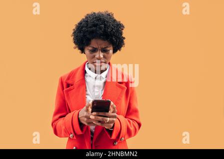 Giovane donna che guarda confuso e preoccupato mentre legge qualcosa sul cellulare. Foto Stock