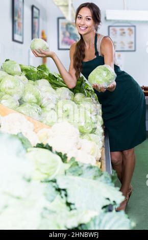 Donna che tiene testa di cavolo fresco sul mercato delle verdure Foto Stock