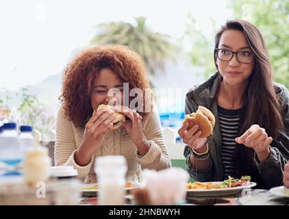 Questo è il posto migliore in città. Scatto corto di un amico che mangia hamburger all'aperto. Foto Stock