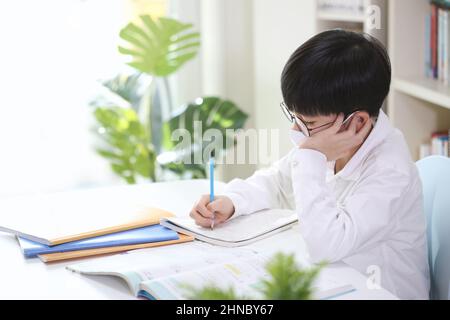 Laurea, ammissione, e nuovo semestre Uno studente carino e intelligente e carino in una maschera che studia duro mentre la concentrazione sta imparando mentre prende le note i Foto Stock