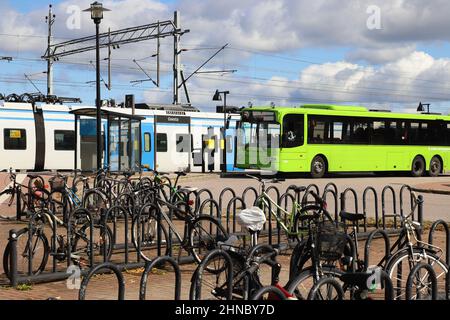 Gnesta, Svezia - 3 settembre 2021: Biciclette di fronte a un autobus pubblico verde alla stazione ferroviaria con un treno pendolare SL. Foto Stock