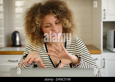 Donna ricurly bianca che parla con web camera. Donna emozionale che parla nel microfono della cuffia e nella webcam del laptop. Imprenditore persona che lavora a casa durante Foto Stock