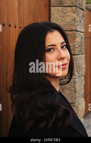 Attraente donna rumena in abito casual scuro appoggiata su una superficie di legno a Lasi, Romania Foto Stock