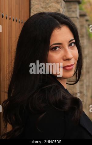 Attraente donna rumena in abito casual scuro appoggiata su una superficie di legno a Lasi, Romania Foto Stock