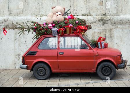 Vintage piccola auto con albero di Natale e un orso giocattolo sul tetto Foto Stock