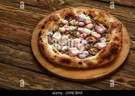 Pizza dolce intera servita con marshmallows e caramelle su sfondo di legno Foto Stock