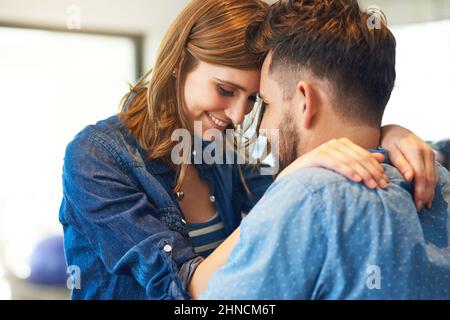 Ha vinto il suo cuore con i suoi abbracci pieni d'amore. Shot di una giovane coppia affettuosa a casa. Foto Stock