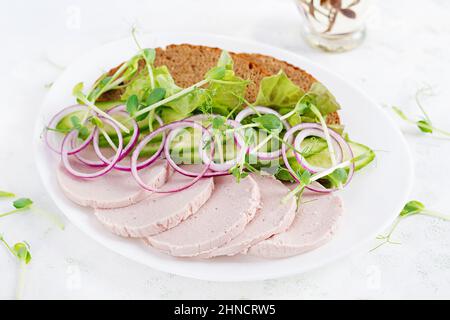 Sandwich con salsiccia di pollo fatta in casa, lattuga e cetriolo nel piatto Foto Stock