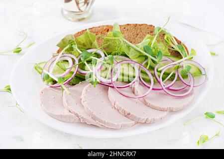 Sandwich con salsiccia di pollo fatta in casa, lattuga e cetriolo nel piatto Foto Stock