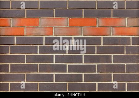 Frammento della parete di un edificio fatto di mattoni di diversi colori. Foto Stock