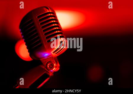 Microfono da palcoscenico classico. Oggetto illuminato con luce colorata. Sullo sfondo, una vista di luci sfocate sul palco. Foto Stock