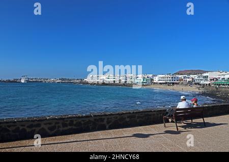 La coppia anziana si è seduta sul panchina guardando la vista di Playa Blanca, Lanzarote Foto Stock