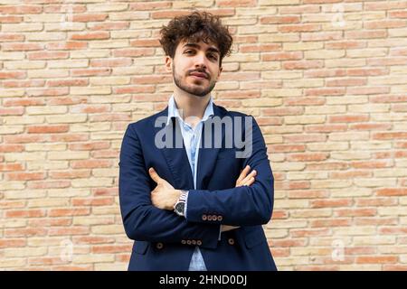 Attraente giovane donna islamica con vestito nero e giacca in pelle e hijab guardando delicatamente la macchina fotografica su studio nero Foto Stock