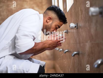 Un giovane musulmano che pulisce il suo volto nella moschea Foto Stock