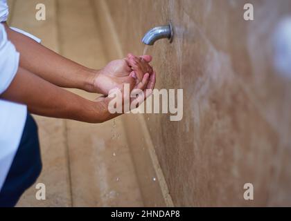 Un uomo musulmano che pulisce le mani nel bagno Foto Stock