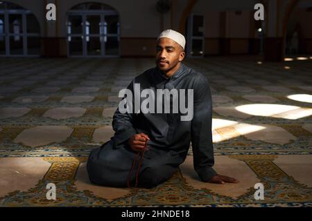 Candido colpo di maschio musulmano seduto sul pavimento in una moschea Foto Stock
