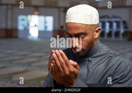 Ritratto di un giovane musulmano che fa dua e prega in una moschea Foto Stock