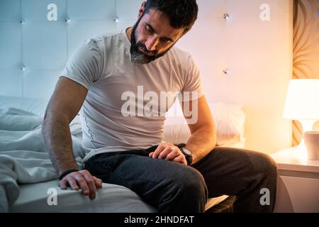 Persona con qualche tipo di problema seduta sul letto e con la vista persa Foto Stock