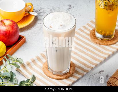 Tè al latte ghiacciato in erba immortale ghiacciata su fondo bianco e stuoia. Bevande fresche e salutari Foto Stock