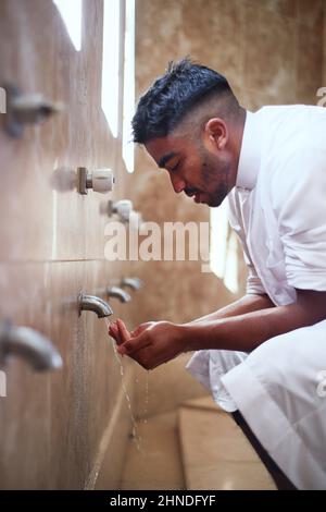 Un giovane musulmano pulisce le mani nel bagno Foto Stock