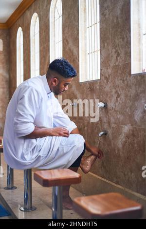 Un uomo musulmano che pulisce i piedi nel bagno della moschea Foto Stock