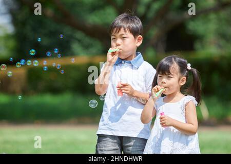 Fratello e sorella giapponese che giocano con le bolle di sapone Foto Stock