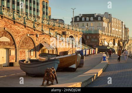 14 gennaio 2022: Brighton, East Sussex, Regno Unito - coppia che cammina oltre le barche, mattina di inizio inverno sulla Promenade di Brighton, East Sussex, Regno Unito Foto Stock