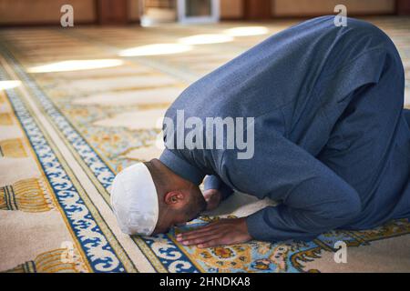 Un giovane musulmano prostrò durante le preghiere in una moschea Foto Stock