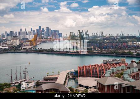 L'enorme porto logistico più trafficato di Singapore, un sacco di gru per spostare container, enormi navi da carico in background, centri commerciali e grattacieli Foto Stock