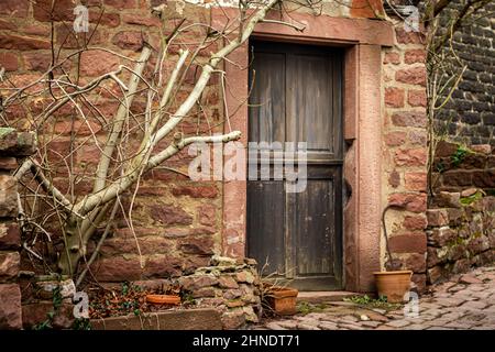 Vecchia porta di legno scuro su rustico capannone in pietra arenaria vicino costruito vecchio villaggio in Germania Foto Stock