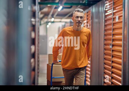 Il dipendente dello Storehouse cammina lungo il corridoio con i container Foto Stock