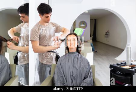 Giovane maschio parrucchiere e cliente ottenere capelli taglio Foto Stock