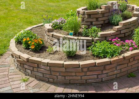 spirale di erbe nel giardino con erbe e fiori Foto Stock