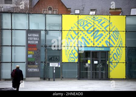 Un uomo cammina fuori dall'ingresso del National Football Museum nel centro di Manchester, Inghilterra, Regno Unito. Foto Stock