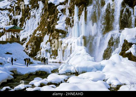 Baramulla, India. 16th Feb 2022. I visitatori sono stati visti accanto alla cascata parzialmente ghiacciata di Drung. Drung, un piccolo villaggio è un bel posto turistico nella zona di Tangmarg di Baramulla. Si trova a circa 50 chilometri dalla capitale Kashmir, Srinagar. Credit: SOPA Images Limited/Alamy Live News Foto Stock