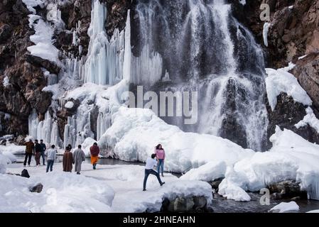 Baramulla, India. 16th Feb 2022. I visitatori sono stati visti accanto alla cascata parzialmente ghiacciata di Drung. Drung, un piccolo villaggio è un bel posto turistico nella zona di Tangmarg di Baramulla. Si trova a circa 50 chilometri dalla capitale Kashmir, Srinagar. Credit: SOPA Images Limited/Alamy Live News Foto Stock