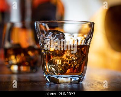 Bicchiere di whisky sulle rocce su un piano bar in legno Foto Stock