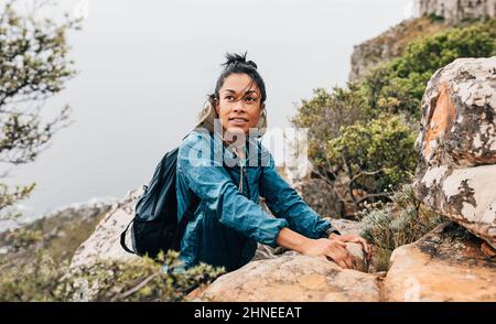 Ritratto di una giovane donna che si rilassa mentre si fa un'escursione in montagna. Donna in abbigliamento sportivo che sale. Foto Stock