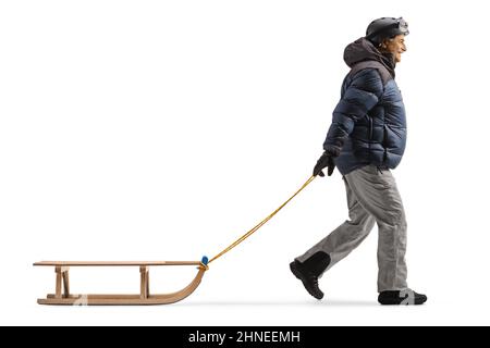 Scatto a tutto profilo di un uomo maturo in abiti invernali tirando una slitta isolata su sfondo bianco Foto Stock