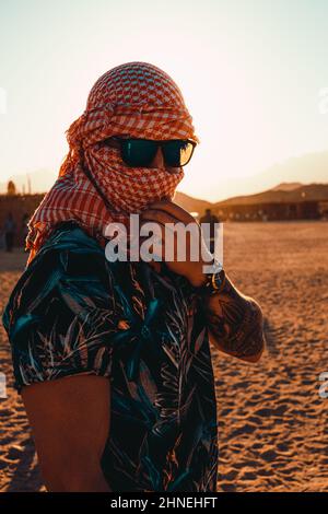 Hurghada Egitto Gennaio 2022 Ritratto verticale di un uomo attraente in piedi nel deserto in un villaggio vicino a hurghada. Bagliore del sole durante il tramonto h Foto Stock