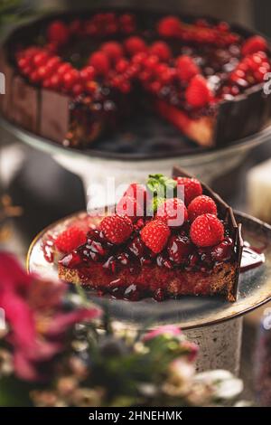 Fetta di torta al cioccolato con salsa di ciliegia e decorata con lamponi freschi Foto Stock