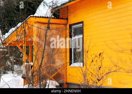 una casa di campagna in legno dipinta di giallo, una scena invernale Foto Stock
